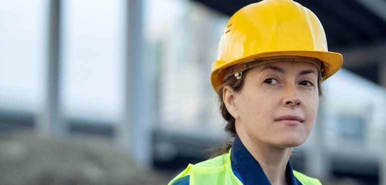 Woman in hard hat looking across site